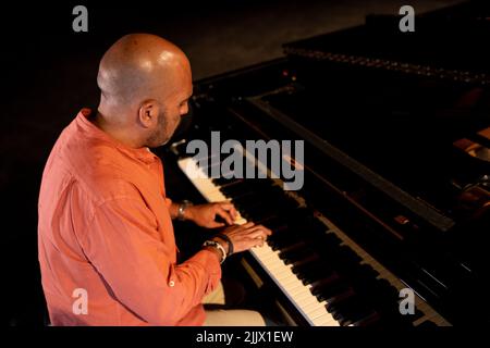 Side view of focus bald male musician playing piano during performance on obscure stage in theater Stock Photo