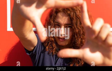Portrait of smiling young Woman gesturing diamond shape Stock Photo