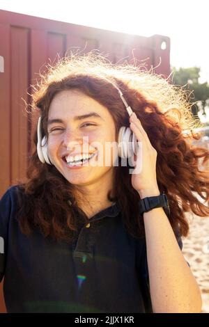 Portrait of young Woman wearing headphones while standing against sky Stock Photo