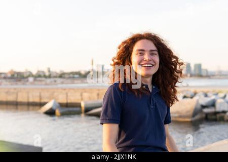 Portrait of Happy Young Woman looking at camera against city port Stock Photo