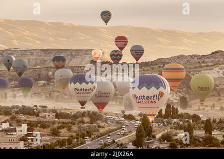 GOREME/TURKEY - June 27, 2022: colorful hot air balloons take flight over the city of goreme at sunrise. Stock Photo