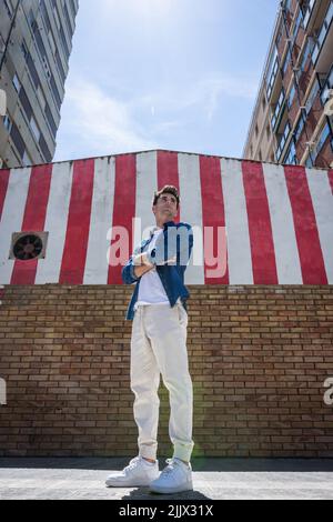 Full length of handsome young man with arms crossed looking away while standing in city Stock Photo