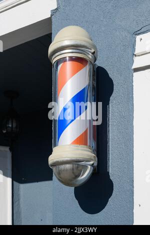 Striped barber pole in glass mounted on a wall with shadow Stock Photo