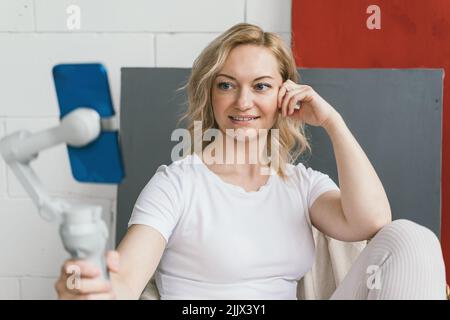 The girl is holding the phone on a tripod.  Stock Photo