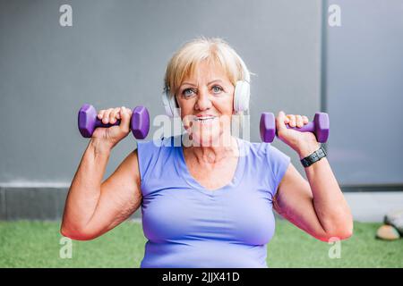 Fit senior Woman exercising with purple dumbbells representing active lifestyle Stock Photo