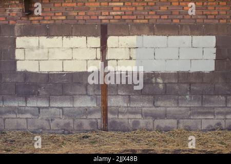 Gray and cream stripe painted on shabby surface of brick wall near straw floor Stock Photo