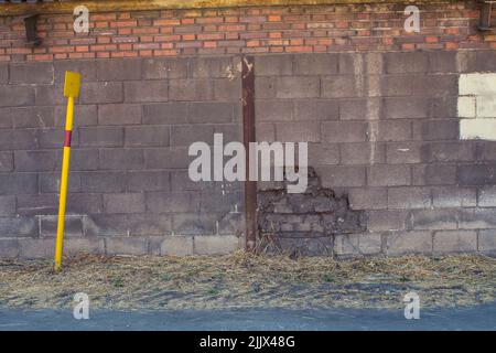 Gray and cream stripe painted on shabby surface of brick wall near straw floor Stock Photo