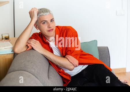 Portrait of young transgender man relaxing on sofa at home Stock Photo