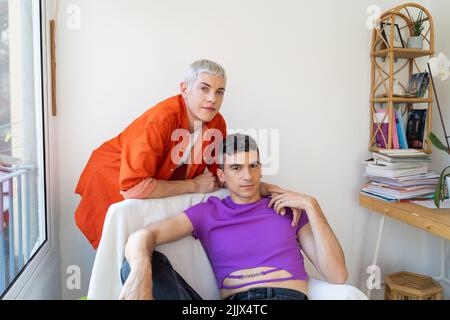 Portrait of loving gay couple sitting on armchair at home Stock Photo