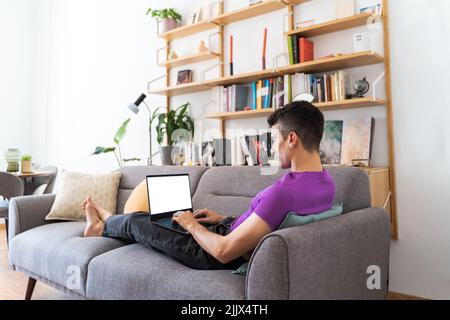Transgender man using laptop sitting on sofa in living room Stock Photo
