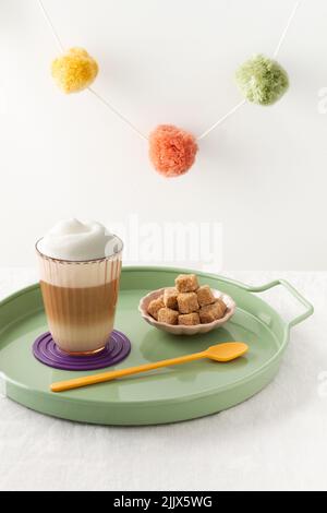 Multilayer coffee or cappuccino in a glass cup and brown sugar cubes in tray Stock Photo
