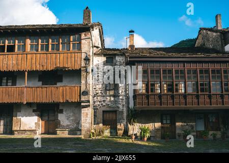 Exterior of aged stone house with shabby doors and balconies located in village on sunny summer day in rural area Stock Photo
