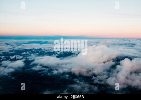 White fluffy cumulus clouds floating over rough mountains covered with snow against cloudless sky in wild nature on winter day Stock Photo