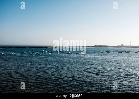 Walled harbor with small boats on the horizon under a blue sky Stock Photo