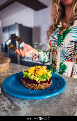 Soft focus of delicious layer salad made of quinoa and beet with avocado and mango and served on plate in kitchen at home