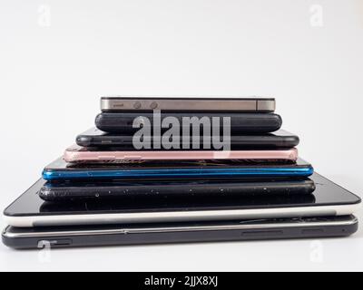 Old smartphones lie on top of each other. Stack of old mobile phones. Smartphones on a white background. Stock Photo