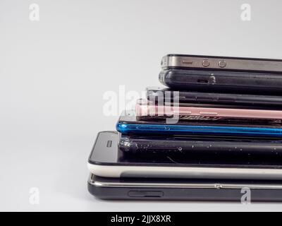 Old smartphones lie on top of each other. Stack of old mobile phones. Smartphones on a white background. Stock Photo