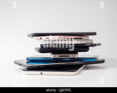 Old smartphones lie on top of each other. Stack of old mobile phones. Smartphones on a white background. Stock Photo