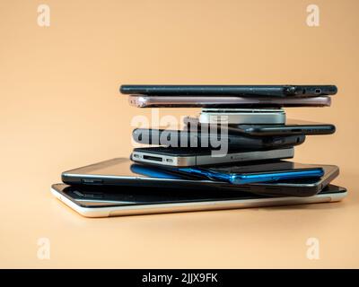 Old smartphones lie on top of each other. Stack of old mobile phones. Smartphones on an orange background. Stock Photo