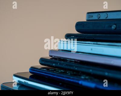 Old smartphones lie on top of each other. Stack of old mobile phones. Smartphones on an orange background. Stock Photo