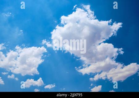 Cumulus clouds against bright blue sky Stock Photo