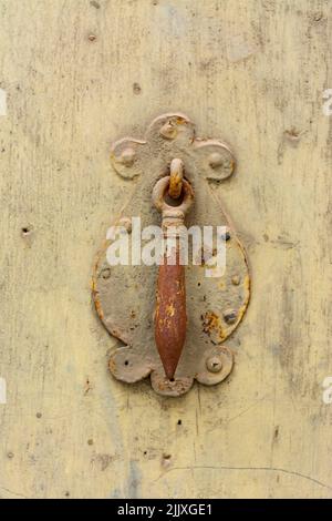 Rusty knocker centered on an old, yellowed wooden door, with copy space Stock Photo