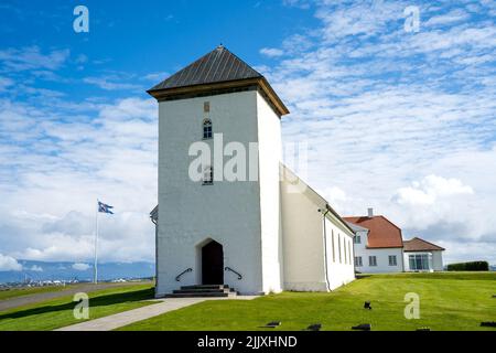 Álftanes, Iceland - July 1, 2022 Landscape view of the church of the Bessastadir, a modest group of white, red-roofed buildings that is the  official Stock Photo