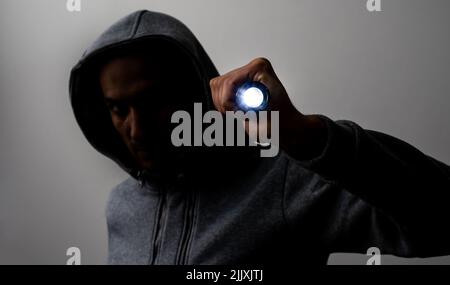 Close up portrait of a courageous man in a deep dark hood on a black background. The concept of secrecy of secrets and people hiding from the Stock Photo