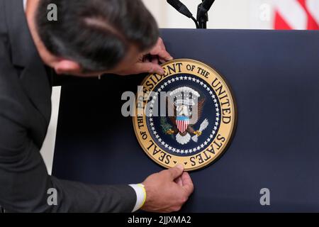 An aide adjusts the seal on the podium prior to United States President Joe Biden delivers remarks on the Inflation Reduction Act of 2022 in the State Dining Room of the White House in Washington, DC on Thursday, July 28, 2022. This legislation, designed fight inflation and lower costs for American families was announced July 27, 2022 by United States Senate Majority Leader Chuck Schumer (Democrat of New York) and US Senator Joe Manchin III (Democrat of West Virginia). Credit: Chris Kleponis/Pool via CNP Stock Photo