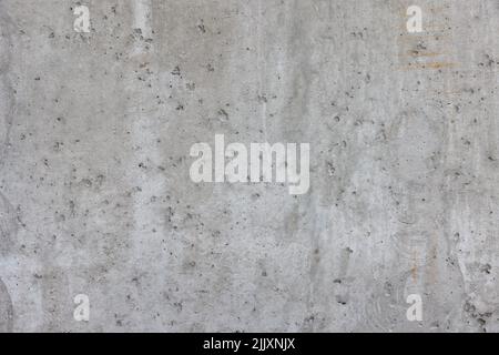 Gray embossed texture of a gray concrete wall with potholes and cracks, abstract background. Stock Photo