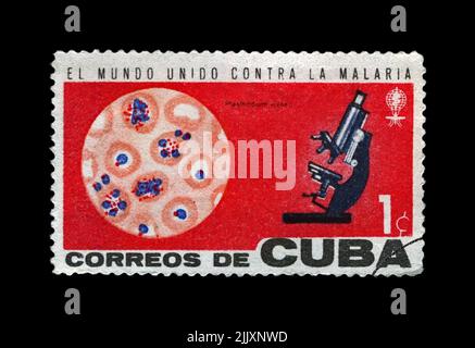 Microscope and blood.. World Health Organization campaign to eradicate malaria, circa 1962. vintage post stamp isolated on black background. Stock Photo