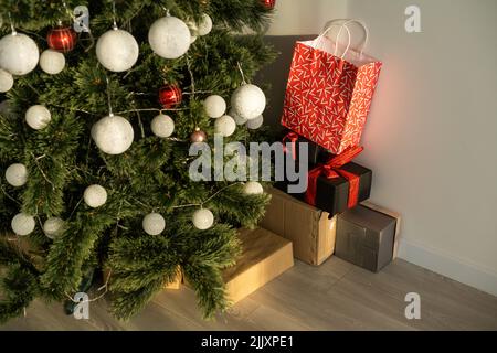 Beautiful Christmas gifts under fir tree on floor in room Stock Photo