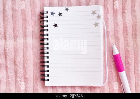 Notebook in hand with stars and pink pen for notes copy space Stock Photo