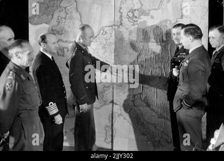 first time the Allied Supreme Command were photographed in conference at their headquarters. General Dwight D. Eisenhower, Supreme Commander, discusses invasion plans with his staff, Left to right:- General Sir Bernard Montgomery, C.-in-C., British Group of Armies; Lt. Gen. Omar N. Bradley, Senior Commander, U.S. Group Forces; Admiral Sir Bertram Ramsay, Allied Naval Commander; General Eisenhower; Air Chief Marshal Sir Trafford Leigh Mallory, Air C.-in-C.; Air Chief Marshal Sir Arthur Tedder, Deputy Supreme Commander; and (behind) Lt. Gen. Walter Bedell Smith, Chief of Staff. February 1, 1944. Stock Photo
