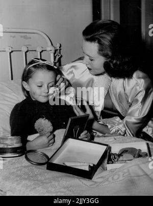 Stage Stars Visit Sick Children -- The leading Stars of the play 'See How They Run' at the Palladium, June Sylvaine (Who plays 'Penelope') & Hector Ross (who plays 'Clive.') Today visited the Alexandra Childrens ward of the Royal prince/ Alfred Hospital. Here, June Gives 5 years old Colleen Haslem a five minute course in the art of Theatre make up... May 17, 1955. (Photo by George Lipman/Fairfax Media). Stock Photo