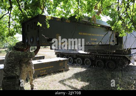 British soldiers assigned to the 26th Regiment Royal Artillery load training rounds into their M270 Multiple Launch Rocket System (MLRS) in the Grafenwoehr Training Area, Germany, July 18, 2022. Dynamic Front 2022, led by 56th Artillery Command and U.S. Army Europe and Africa directed, is the premiere U.S.-led NATO Allies and Partners-integrated fires exercise in the European theater focusing on fire interoperability and increasing readiness, lethality and interoperability across the human, procedural and technical domains.(U.S. Army photo by Maj. Joe Bush) Stock Photo