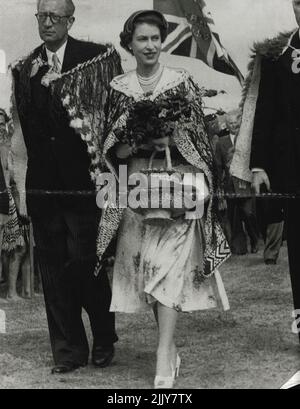 Gifts - Queen Elizabeth ***** charming and happy as she leaves a Maroi ceremony at Arawa Park, Rotorua, in a Maori chief's cloak. The Queen is carrying gifts of flowers and two baskets. January 07, 1954. Stock Photo