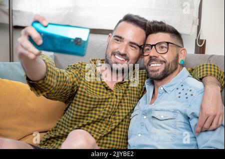 Young smiling gay couple taking selfie at home. High quality photography Stock Photo