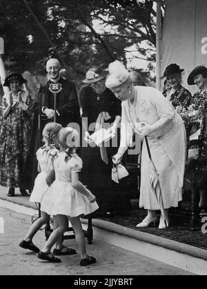 Queen Mary Opens Part Of Newnham College Extension Scheme -- Two little children presenting purses to Queen Mary in aid of the building fund, at Newnham College today. H.M. Queen Mary today visited Newnham College, Cambridge, to open a residential block, the first portion of a £100,000 extension scheme for the college. The building has been designed by Miss Elizabeth Whitworth Scott, the architect who designed the Shakespeare Memorial Theatre at Stratford. August 12, 1938. (Photo by Topical Press). Stock Photo