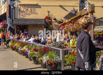 People are eating outdoors in historic district of Victoria BC on sunny summer day. Tourists Having Lunch At street restaurant. Travel photo, selectiv Stock Photo