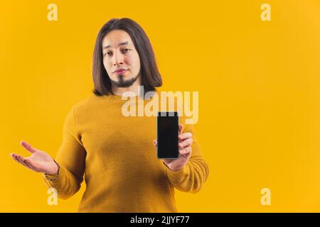 An isolated bearded European guy in his 30s showing screen of his phone in a studio. High quality photo Stock Photo