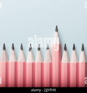 Abstract background of pink pencils lying in a row on blue background. Colour concept Stock Photo