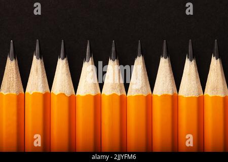 Abstract background of orange pencils lying in a row on black background. Colour concept Stock Photo