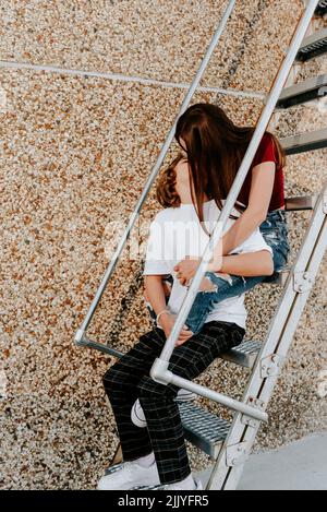 teenage couple kissing while sitting on stairs Stock Photo