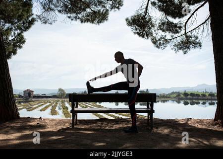 Silhouette of man doing stretching exercise Stock Photo