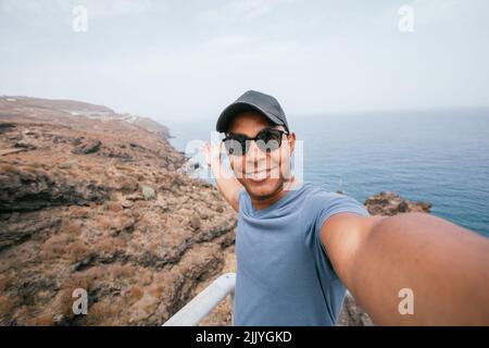 Latin man taking selfie from mountains off coast of island of Tenerife Stock Photo