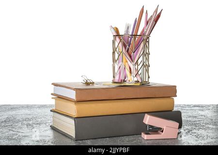 Cup with school stationery and books on table against white background Stock Photo