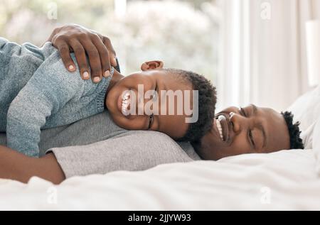 Dads more comfortable than my bed. Cropped portrait of an adorable little boy lying on his fathers chest on a bedroom at home. Stock Photo