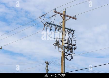 A wooden pillar is on instaled with electrical wires, cables Stock Photo