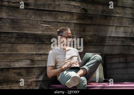 Young man remote worker web developer using laptop, working online at outdoor coworking space Stock Photo